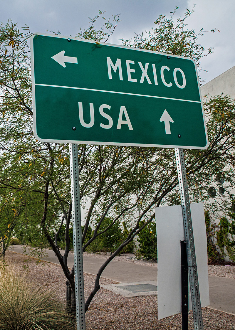 Traffic sign showing Mexico to the left and USA straight ahead